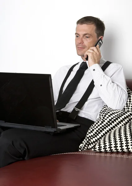 businessman sitting on couch with phone and labtop