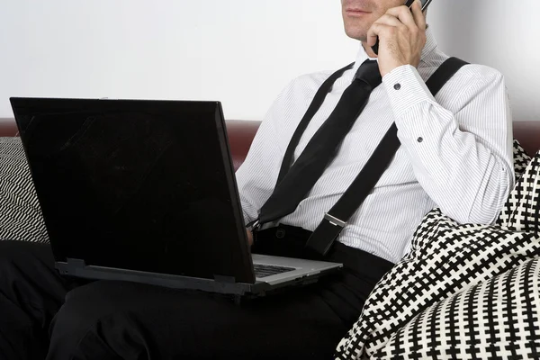 Affärsman som sitter på soffan med telefonen och labtop — Stockfoto