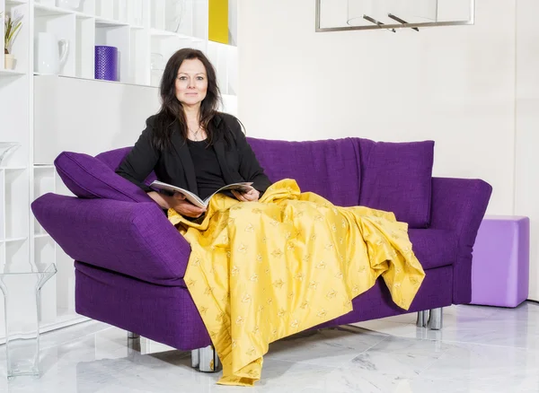 Mujer en sofá con revista —  Fotos de Stock