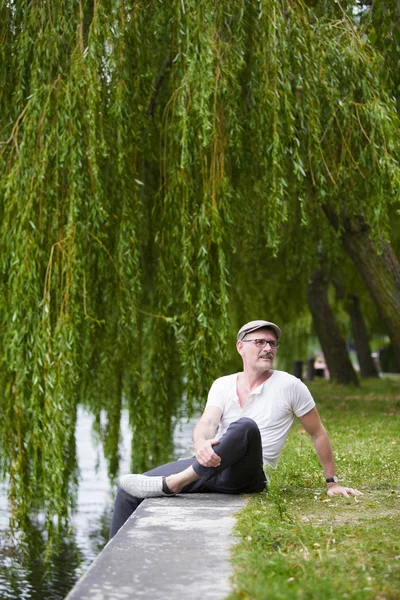 Mann sitzt am Wasser — Stockfoto