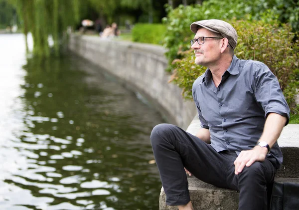 Mann sitzt am Wasser — Stockfoto