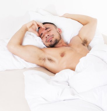 Adam yatakta uyuyor.