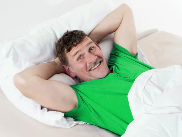 Mann im Bett lächelt — Stockfoto