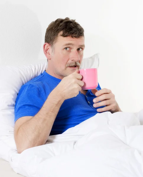 Man in bed met cup — Stockfoto