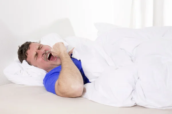 Hombre en la cama bostezando — Foto de Stock