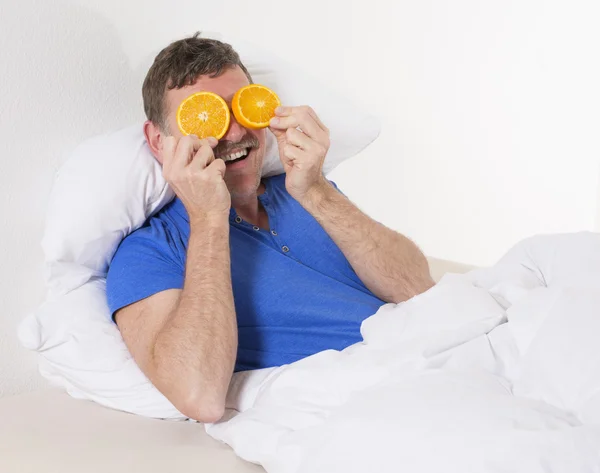 男人在床上用橘子 — 图库照片