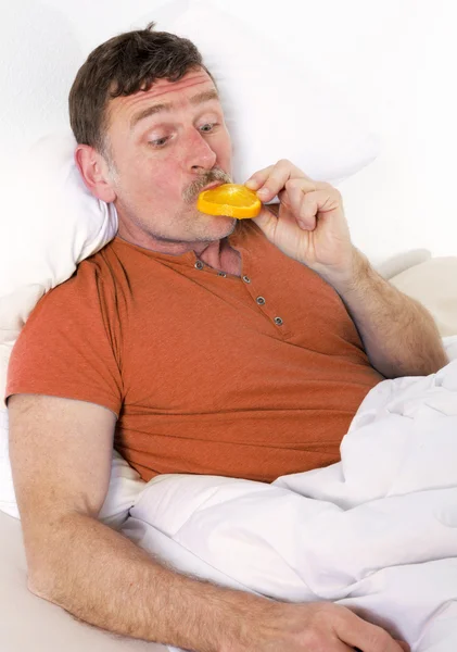 Mann im Bett mit Orangen — Stockfoto