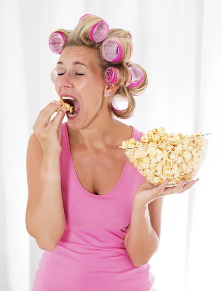 Kvinna med papiljotter äta popcorn — Stockfoto