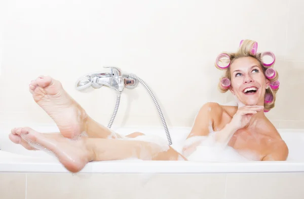 Kvinna med papiljotter i badkar — Stockfoto
