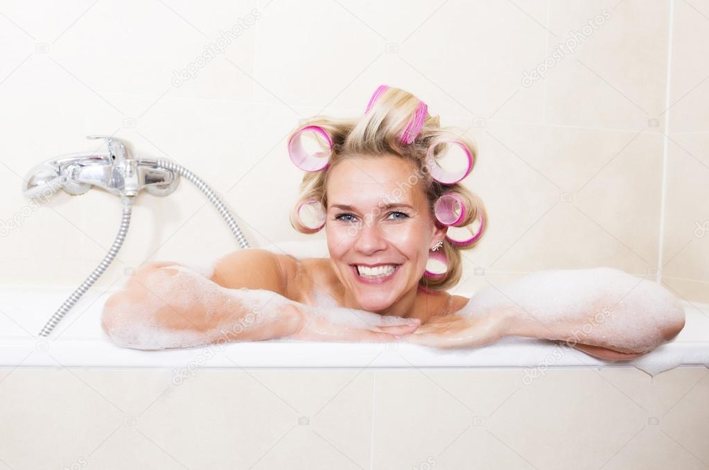 Woman with curlers in bathtub