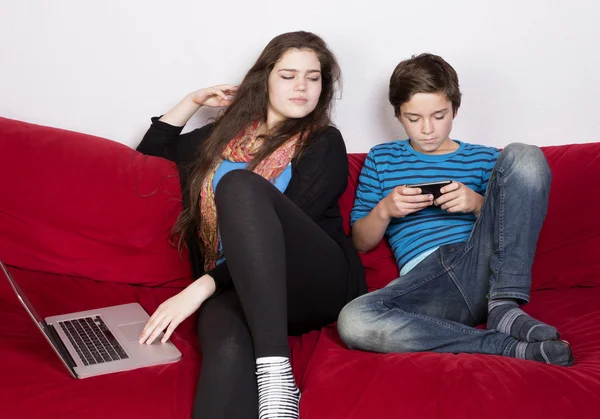 Niña y niño con ordenador portátil y teléfono —  Fotos de Stock