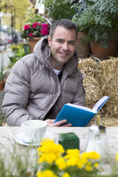 Homme assis dehors et lisant un livre — Photo