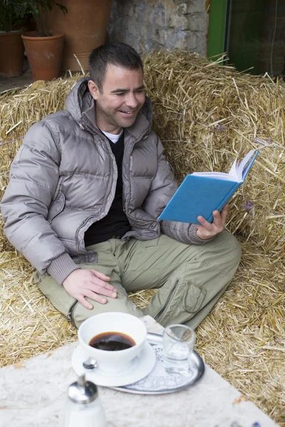 Hombre sentado afuera y leyendo un libro — Foto de Stock