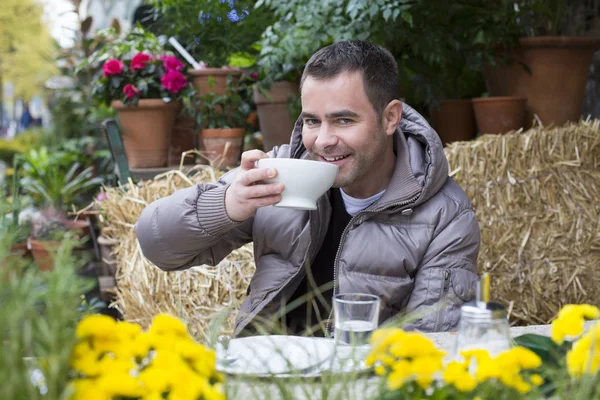 Hombre sentado afuera con una taza en sus manos — Foto de Stock
