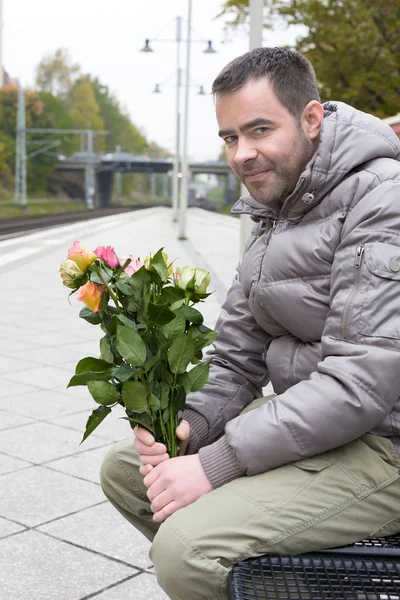 Férfi vasútállomáson virágok vár — Stock Fotó