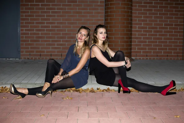 Two women sitting on a curb — Stock Photo, Image