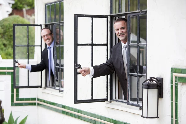 Dos hombres de negocios mirando por una ventana — Foto de Stock