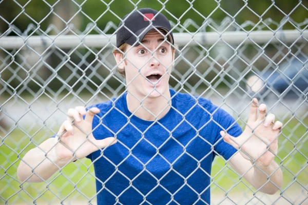 Ung man hänger på staket på sportsfield — Stockfoto