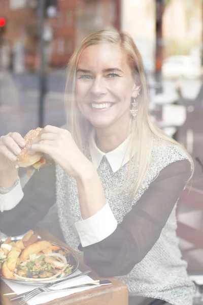 Mujer con hamburguesa mirando por la ventana — Foto de Stock