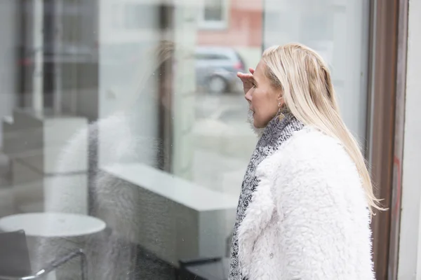 Woman looking through a window — Stock Photo, Image