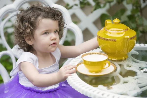 Çaydanlık ile bahçede oturan yürümeye başlayan çocuk — Stok fotoğraf