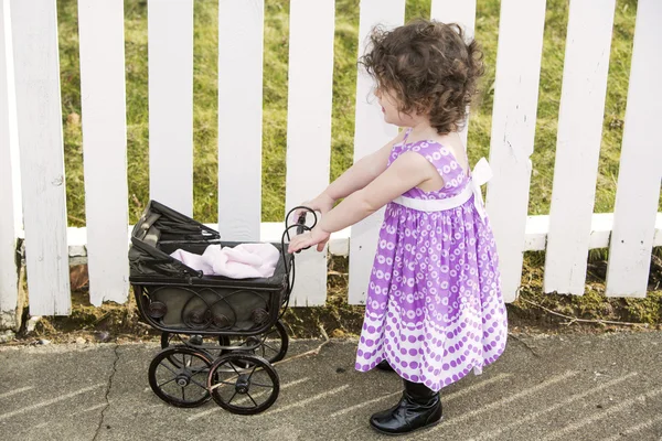 Little girl pushing a vintage stroller — Stock Photo, Image