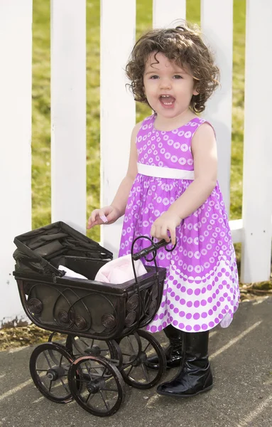 Çocuk arabası ile pembe elbiseli küçük kız — Stok fotoğraf