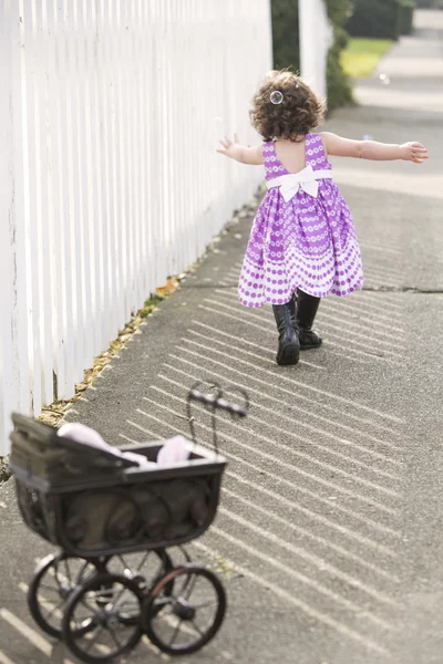 Bambina in abito rosa a caccia di bolle di sapone — Foto Stock