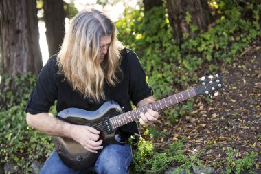 adam bir parkta gitar çalmak