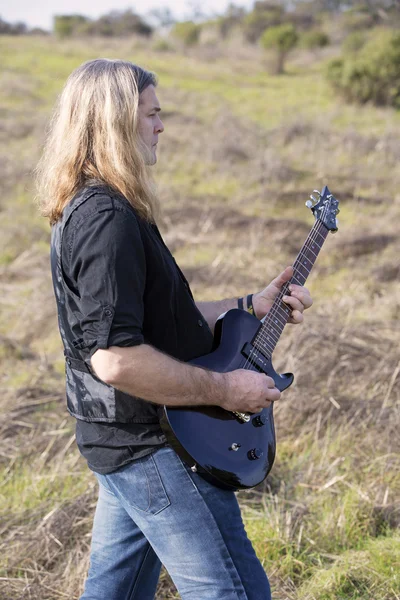 Homem com guitarra em um campo — Fotografia de Stock