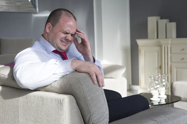Geschäftsmann sitzt mit Kopfschmerzen auf Couch — Stockfoto