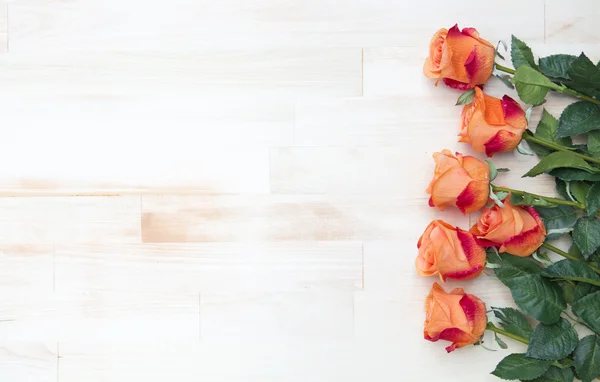 Rosas naranjas sobre fondo blanco rústico de madera — Foto de Stock