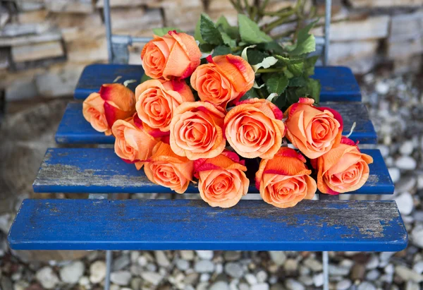 Оранжевые розы на синем деревенском стуле — стоковое фото