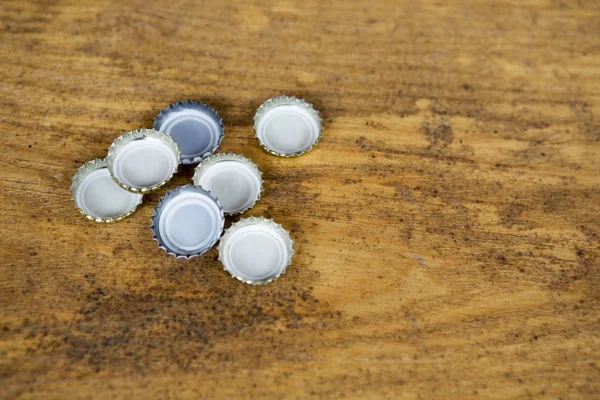 Bottle caps on rustic wooden background — Stock Photo, Image