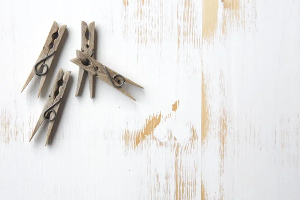 Cuatro pinzas de ropa sobre fondo de madera blanco — Foto de Stock