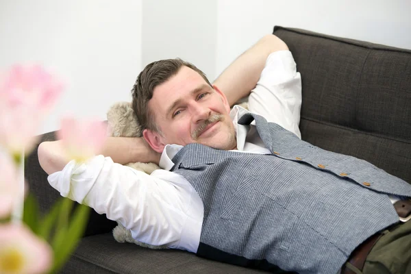 Muž ležel na gauči a usmívá se — Stock fotografie