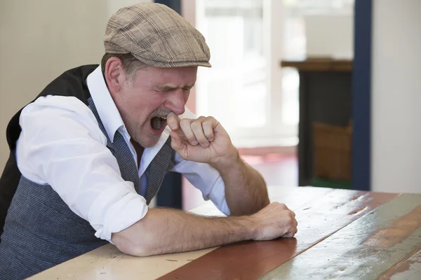 Man sitting at table and yawns — Stock Photo, Image