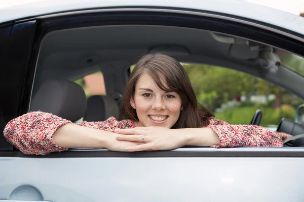 Portret van een jonge vrouw in een auto zit — Stockfoto