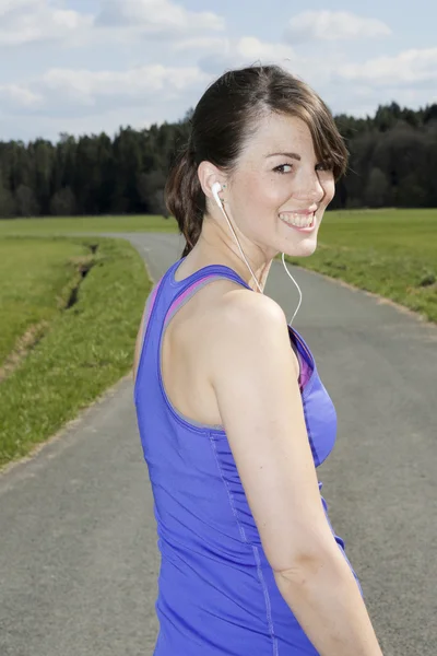 Kulaklıklar ile egzersiz giysili genç kadın — Stok fotoğraf