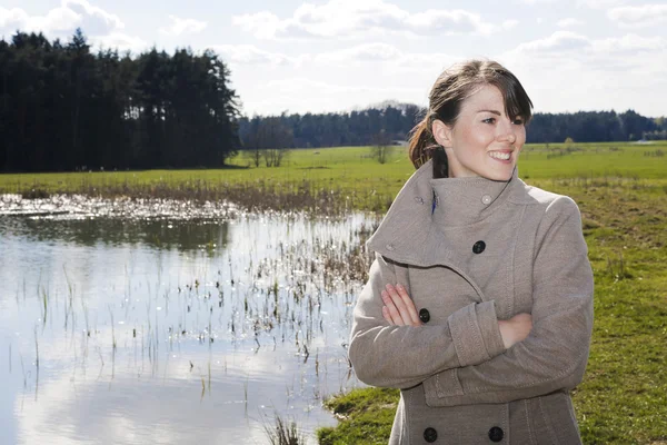 Femme en manteau debout au bord d'un lac — Photo