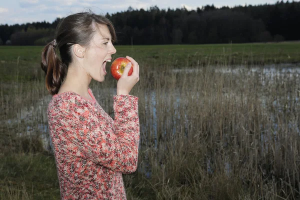 Young woman eating an apple outdoors — Stock Photo, Image