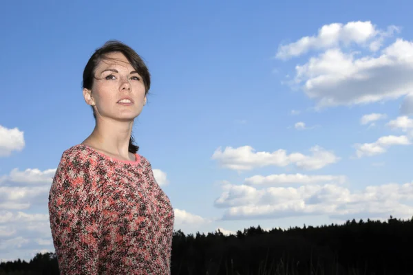 Porträtt av en ung kvinna framför en blå himmel — Stockfoto