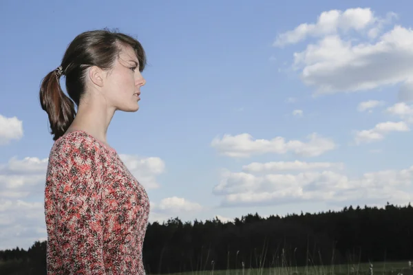 Portrait of a young woman in front of a blue sky — Stock Photo, Image