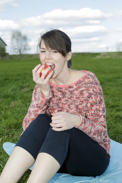 Young woman eating an apple outdoors — Stock Photo, Image