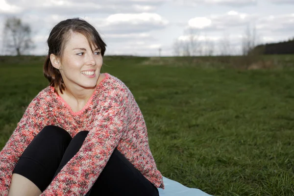 Young woman sitting outdoors on grass — Stock Photo, Image