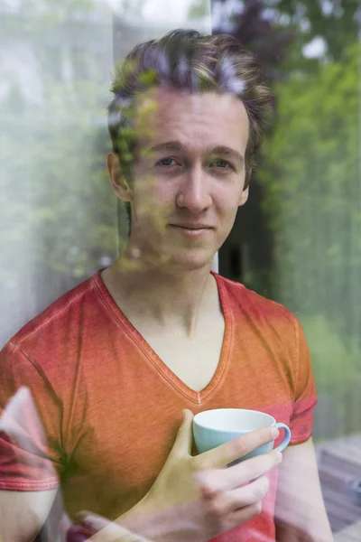 Young blond man looking out of window — Stock Photo, Image