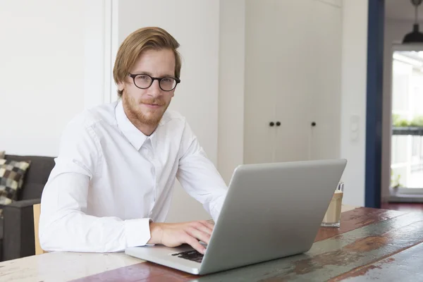 Молодой человек сидит в гостиной со своим ноутбуком — стоковое фото