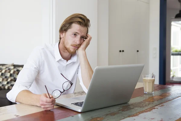 Fiatal ember ül a laptop, és keresi a szomorú — Stock Fotó