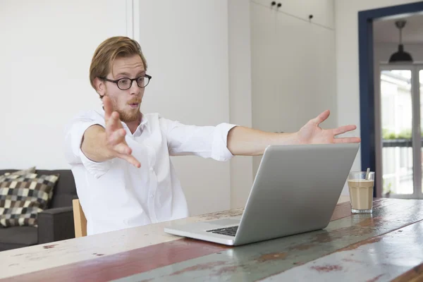 Ung man sitter med sin laptop och ser stressad och spänningen — Stockfoto