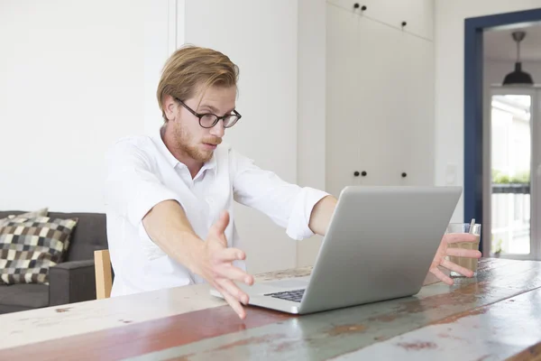 Giovane seduto con il suo computer portatile e guardando stressato ed eccit — Foto Stock